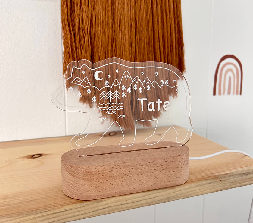 Decorative lamp with bear design and custom name 'Tate' on a wooden base, placed on a shelf.